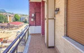 Un balcone con ringhiera in metallo, un muro di mattoni e una persiana chiusa.