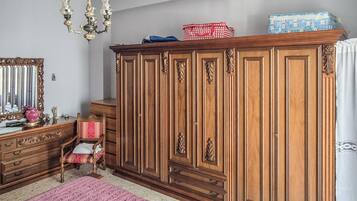 A room with a large wooden wardrobe, a mirror, a chandelier, and a patterned rug.