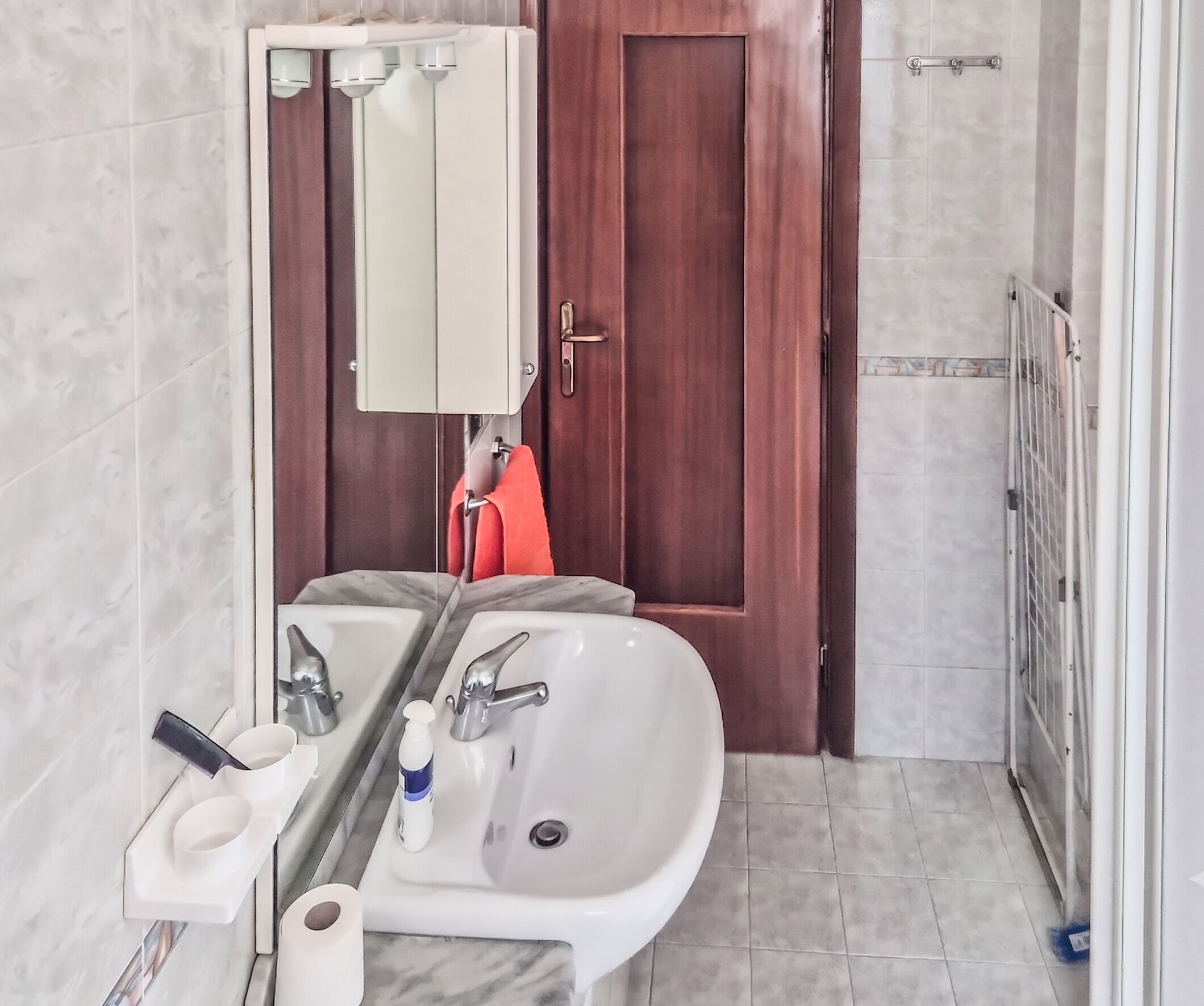 A bathroom with two sinks, a mirror, a towel rack, and a shower area.