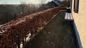 Asfaltoitu kävelytie kulkee rakennuksen vieressä, taivaalla on sinistä ja aurinko paistaa.