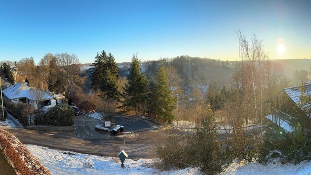 Asuinalue, jossa on taloja, lumipeitteinen maa ja kirkas taivas.