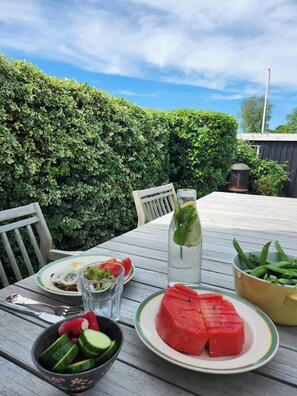 A table set outdoors with plates of food, a bottle of water, and a bowl of vegetables. - Family holiday home on Als with sauna and shelter (Sydals)