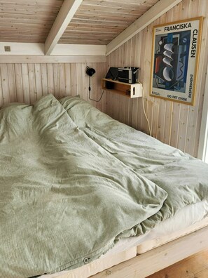 A single bed with a green striped bedspread, a wooden ceiling, and a poster on the wall. - Family holiday home on Als with sauna and shelter (Sydals)