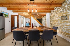 A dining area with a wooden table, six chairs, and a stone wall. - Casa Rosina in Šestani - Haus für 4-5 Personen (Zarecje)