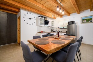 Una cocina moderna con vigas de madera en el techo, un reloj y un comedor con mesa y sillas de madera.