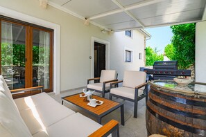 Un patio con mobiliario exterior, una parrilla y un barril decorativo.