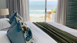 Habitación de hotel con una cama, vista al océano y una silla afuera.