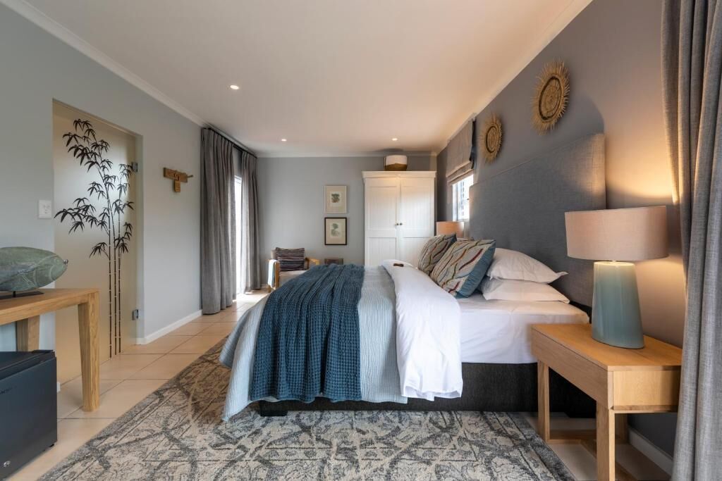 Un dormitorio con cama, mesitas de noche, lámpara, estante en la pared y un adorno mural.