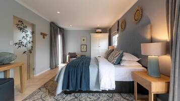 Un dormitorio con cama, mesitas de noche, lámpara, estante en la pared y un adorno mural.