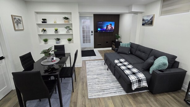 A modern living room with a sofa, dining table, chairs, a TV, and decorative plants.