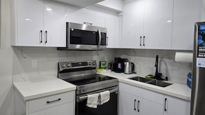 A modern kitchen with white cabinets, stainless steel appliances, and a marble backsplash.