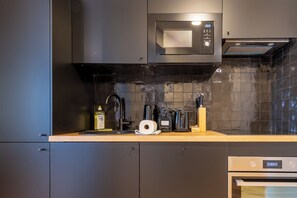 A modern kitchen with a microwave, coffee maker, and a wooden countertop. - Beautiful and Modern 1BDR Flat near Montmartre (Paris)