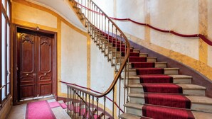 Eine prächtige Treppe mit rotem Teppich, verzierten Holztüren und einer Marmorwand.