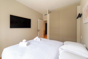 Hotellihuone, jossa on sänky, taulutelevisio ja ovi, joka johtaa kylpyhuoneeseen.
