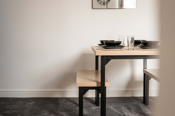A dining table with black plates, glasses, and a wooden bench.