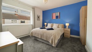 A bedroom with a bed, bedside tables, a window, and a view of a house. - Cleethorpes Home Near Beach, Free Parking, Fast (Cleethorpes)