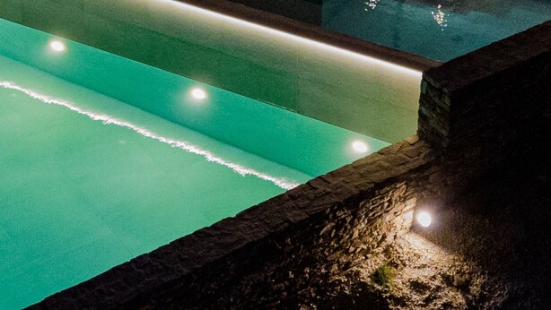 Uma área de piscina no terraço, com espaço para sentar e vista do edifício.