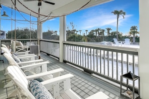 A covered outdoor seating area with white chairs and a view of the water. - 🌊 Arlanymor | Windmark Beach | Private Pool, Volleyball + Beach Access (Windmark)