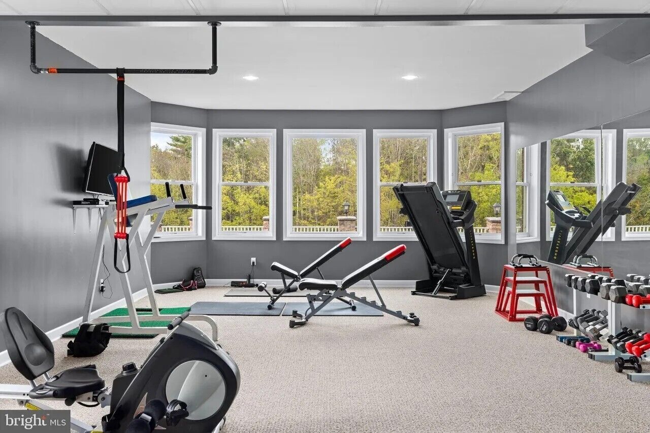 A gym with exercise equipment, windows, and a view of trees.