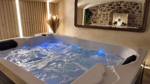 Un jacuzzi con una pared de piedra y un espejo que refleja la habitación.