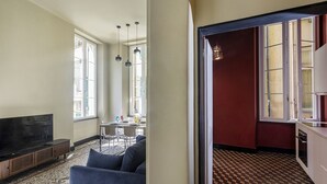 Ein Wohnzimmer mit Fernseher, einer Couch und einem Essbereich mit Tisch und Stühlen.