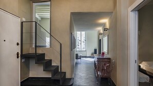 Ein Flur mit Treppe, Essbereich und Bett.