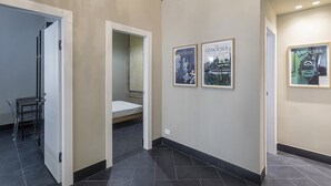 Ein Korridor mit einem Bett, einem Sessel und gerahmten Bildern an der Wand.