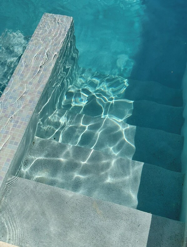 A clear pool with a tiled edge and visible water patterns.