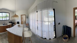 A compact kitchen with a granite countertop, a sink, a stove, and a refrigerator. There is a dining area with a table and chairs.