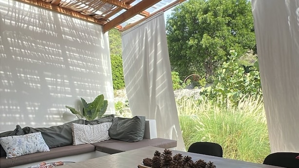 A covered outdoor seating area with a table, chairs, and a ceiling fan.