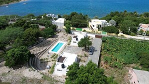 A coastal property with a swimming pool, multiple buildings, and a view of the sea.