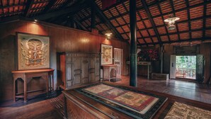 Una habitación con paredes y techo de madera, un tapiz grande y un tapiz enmarcado.
