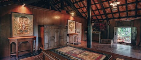 A room with wooden walls and ceiling, a large rug, and a framed tapestry.