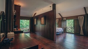 A room with a wooden floor, a bed, a bench, and a view of greenery outside. - Hok Sokol's Villa by Ream Lek (Krong Siem Reap)