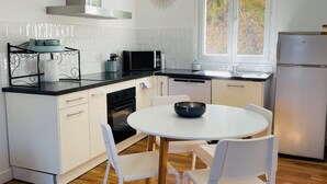 Una cucina moderna con mobili bianchi, una cappa aspirante in acciaio inossidabile, un forno a microonde e un frigorifero.