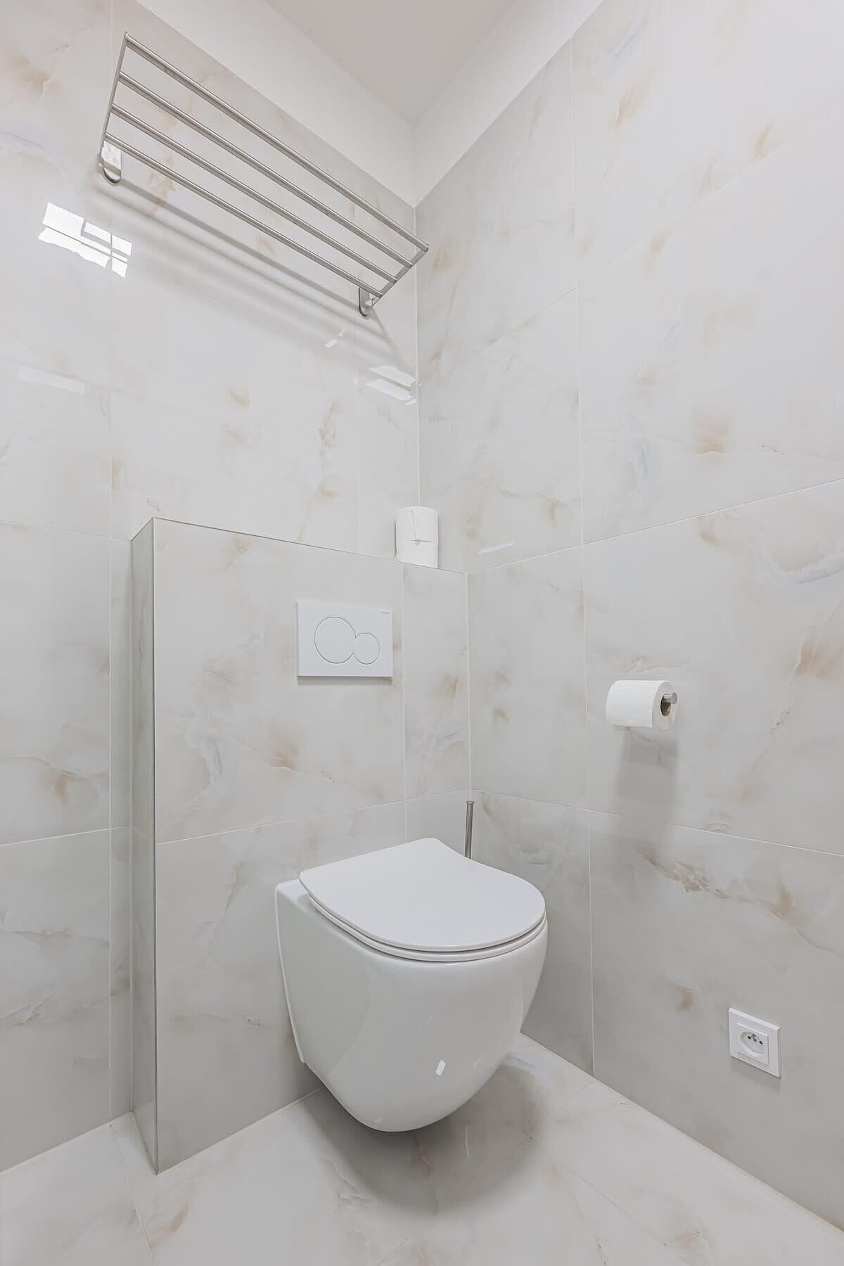 A modern bathroom with a toilet, a shower, and a towel rack.