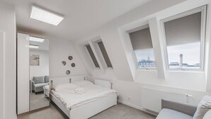Quarto com cama, sofá, janela com vista, radiador e luminária de teto.