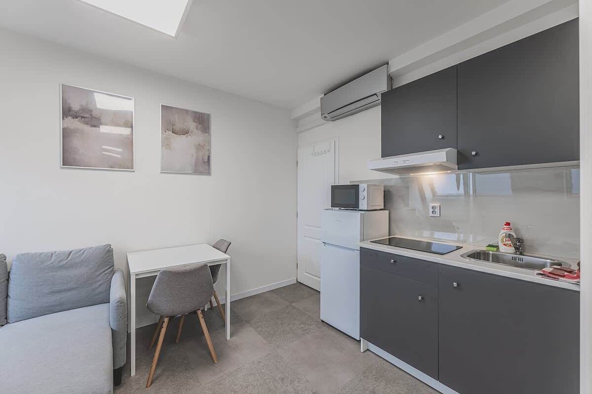 A compact kitchen with a dining area, a white refrigerator, a microwave, and a sink.