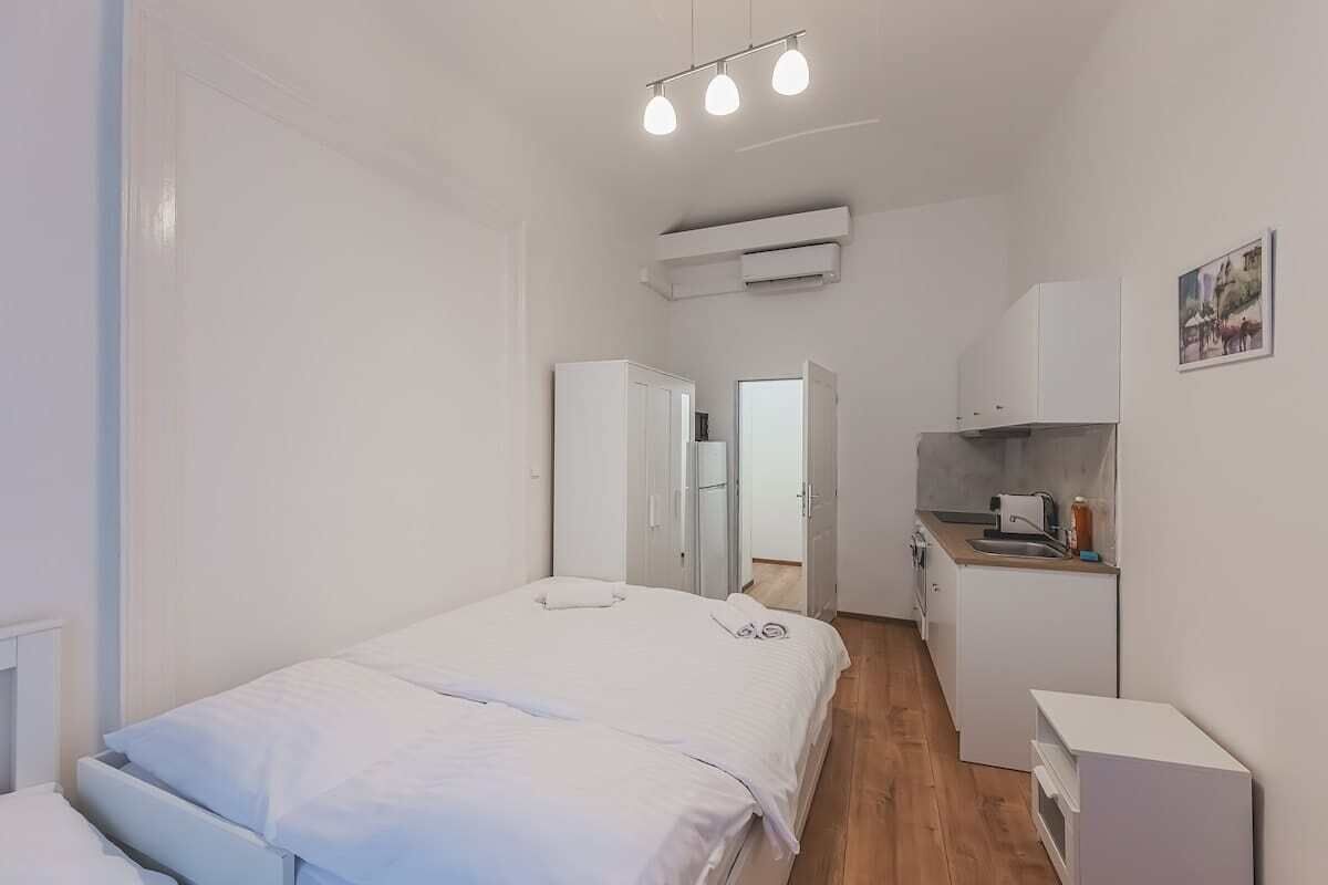 Une chambre comprenant un lit, une armoire, un coin cuisine et un appareil de climatisation.