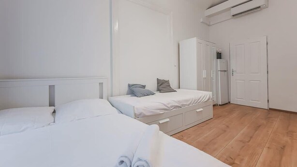 Een slaapkamer met twee bedden, een kledingkast, een deur en een airconditioning.