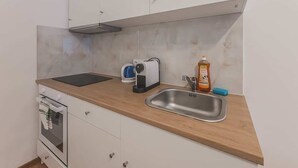 Een compacte keuken met een inbouwoven, een koffiezetapparaat, een broodrooster en een spoelbak.