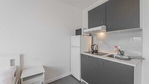 Uma cozinha compacta equipada com micro-ondas, mini-geladeira, pia e bancada.