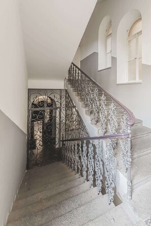 Eine Treppe mit aufwendiger Metallreling und Steinlaufgeländer.