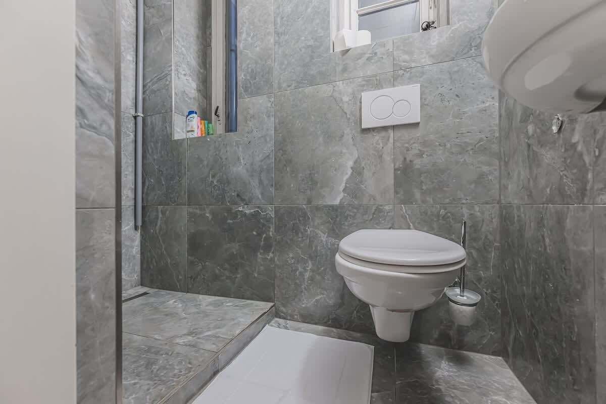 Ein Badezimmer mit Toilette, einer Dusche und einer kleinen Ablage für Toilettenartikel.