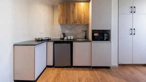 Una cocina compacta con encimera negra, microondas integrado y cafetera.