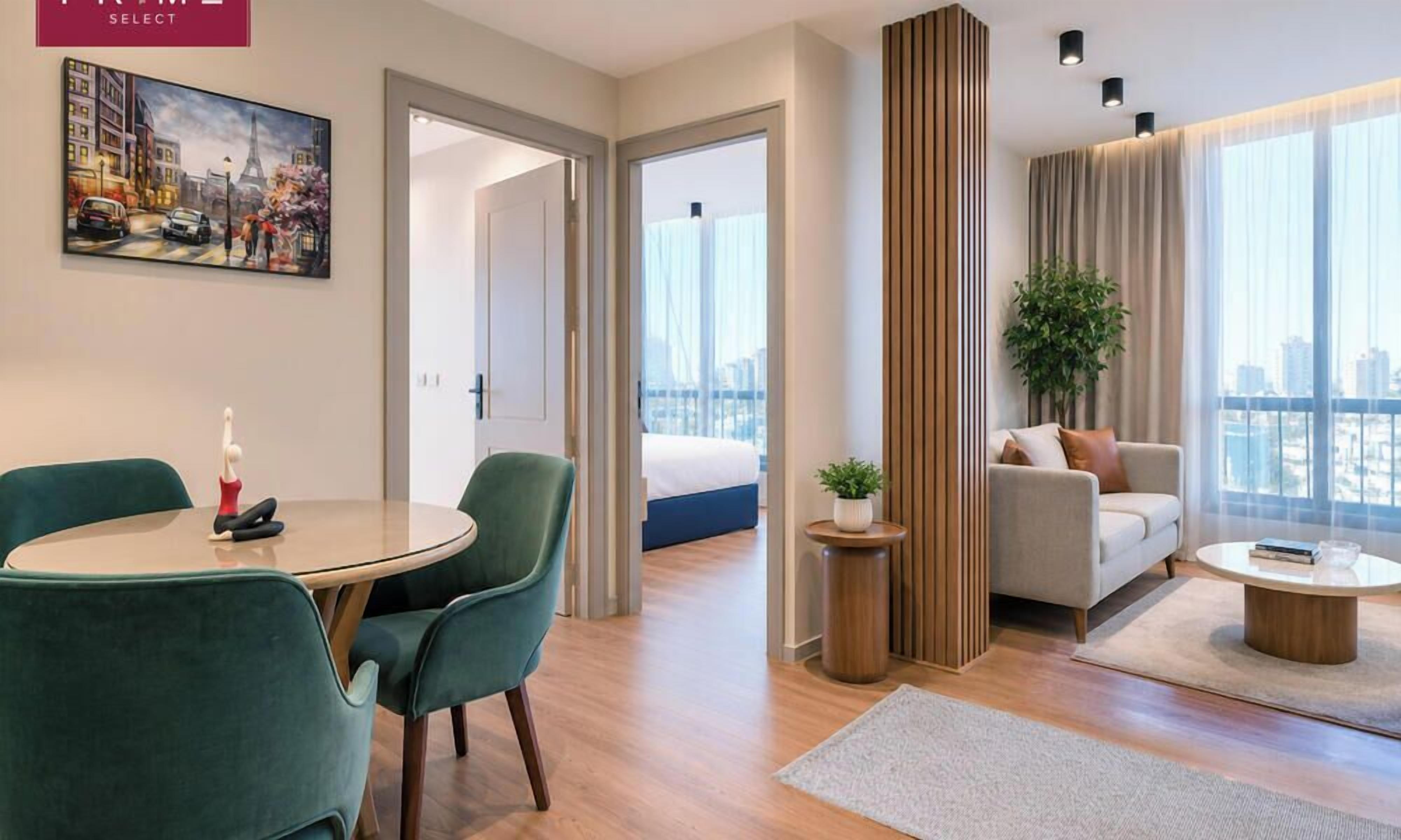 A modern hotel room with a dining area, a sofa, a bed, and a view of the city.