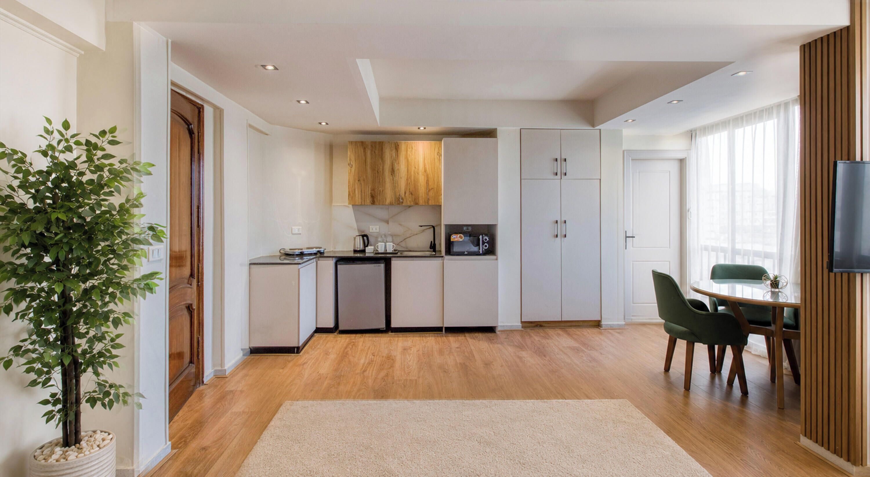 A modern kitchen with wooden cabinets, a built-in oven, and a dining area with a table and chairs.
