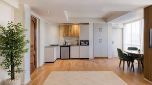 Una cocina moderna con armarios de madera, horno empotrado y comedor con mesa y sillas.