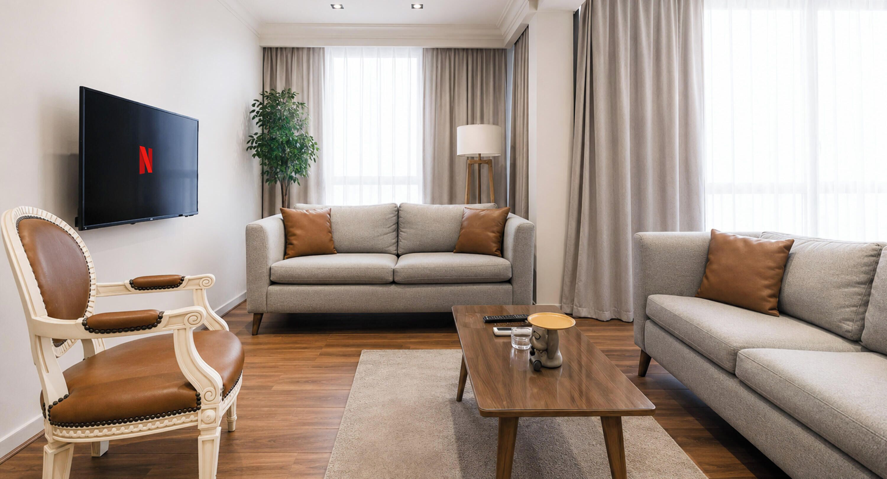 Una sala de estar con un conjunto de sofá, una mesa de centro, un televisor montado en la pared y una planta en maceta.