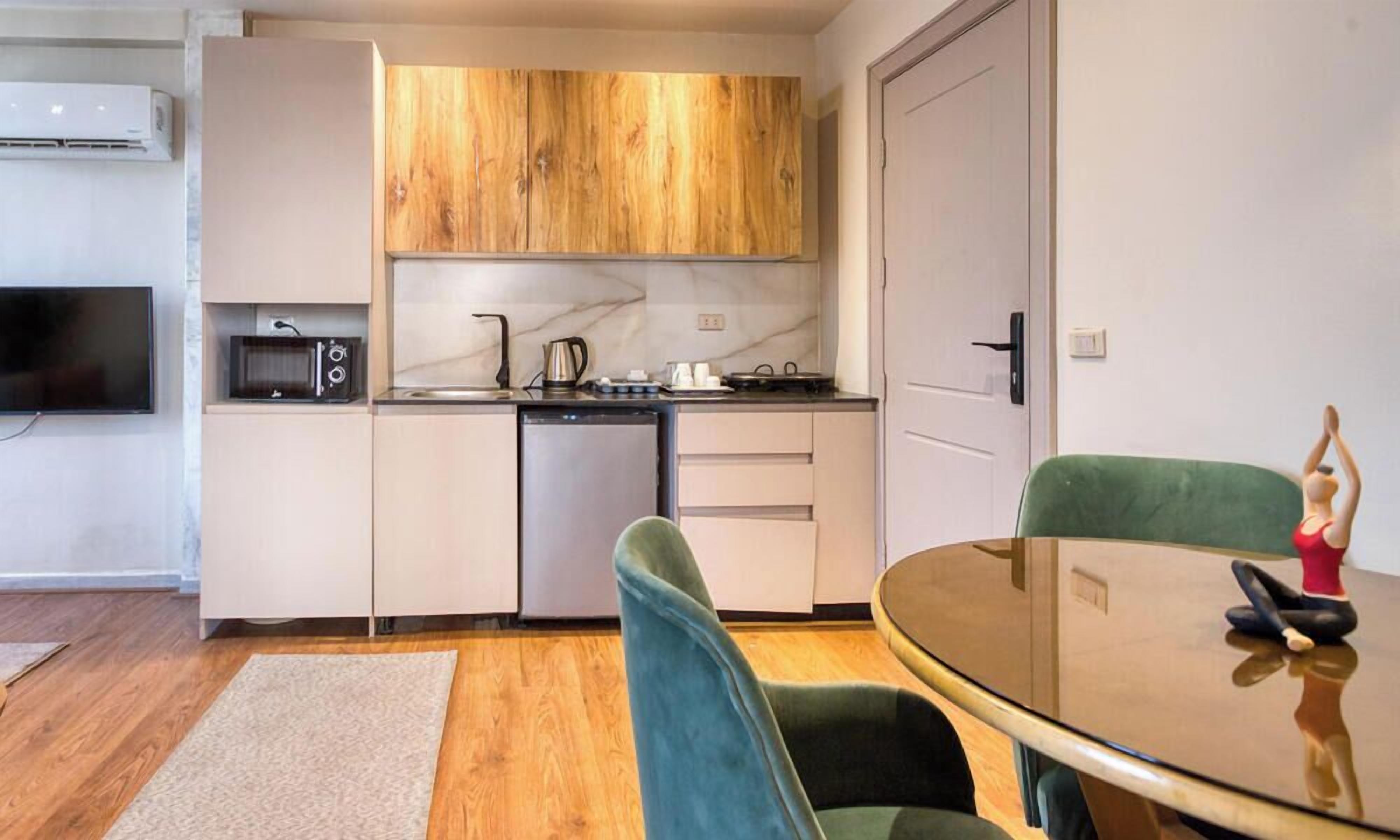 A compact kitchen with a microwave, stove, and cabinets. There is a dining area with a table and chairs.